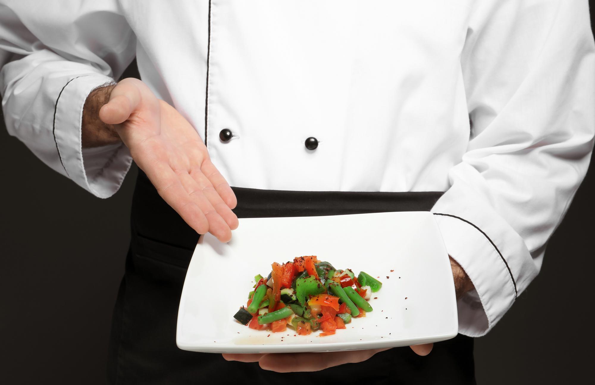 Chef demonstrating plating technique in elegant kitchen